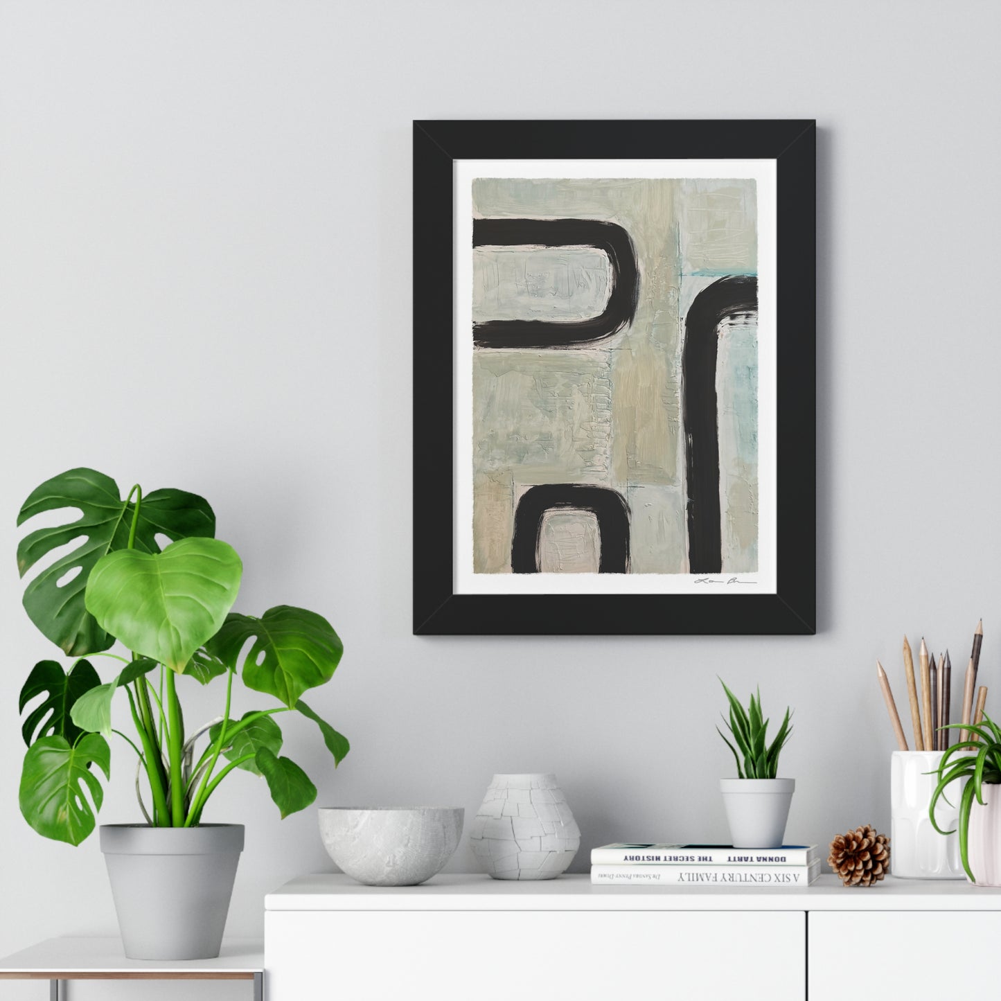 Framed abstract art piece on a wall with decorative items below