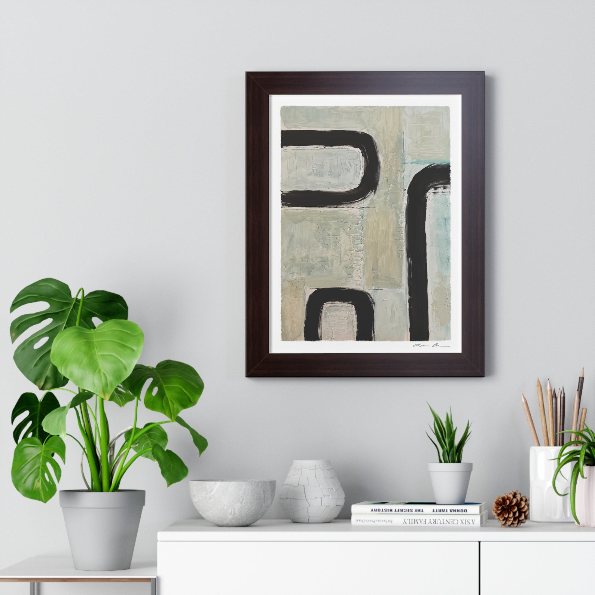 Framed abstract art piece on a wall with decorative items below